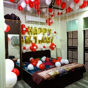 Jaipur room birthday balloon decoration with red-white theme and golden foil banner