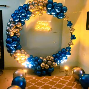 A circular metallic blue and gold balloon arch with a "Happy Birthday" neon sign for a birthday celebration.