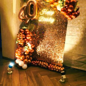 Elegant 40th birthday decoration in Jaipur with a rose gold sequin wall, neon sign, and a large metallic balloon arch by Manhagift.